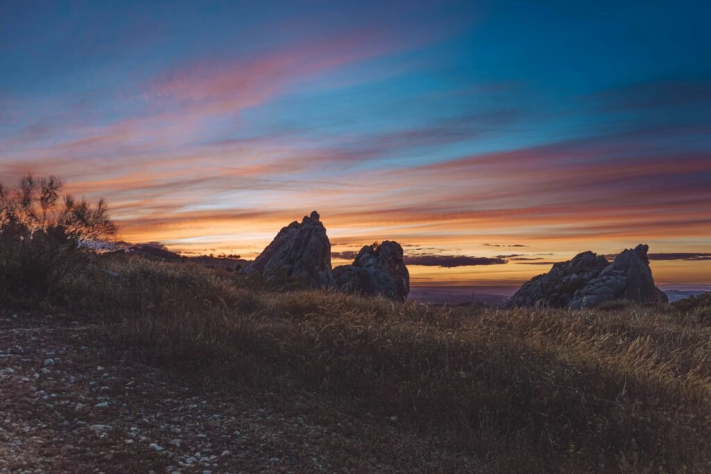 the sun is setting over the rocky terrain
