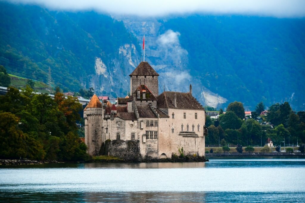 a castle sitting on top of a lake surrounded by mountains