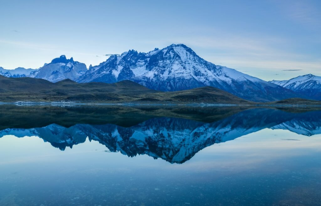 snow covered mountain near body of water during daytime